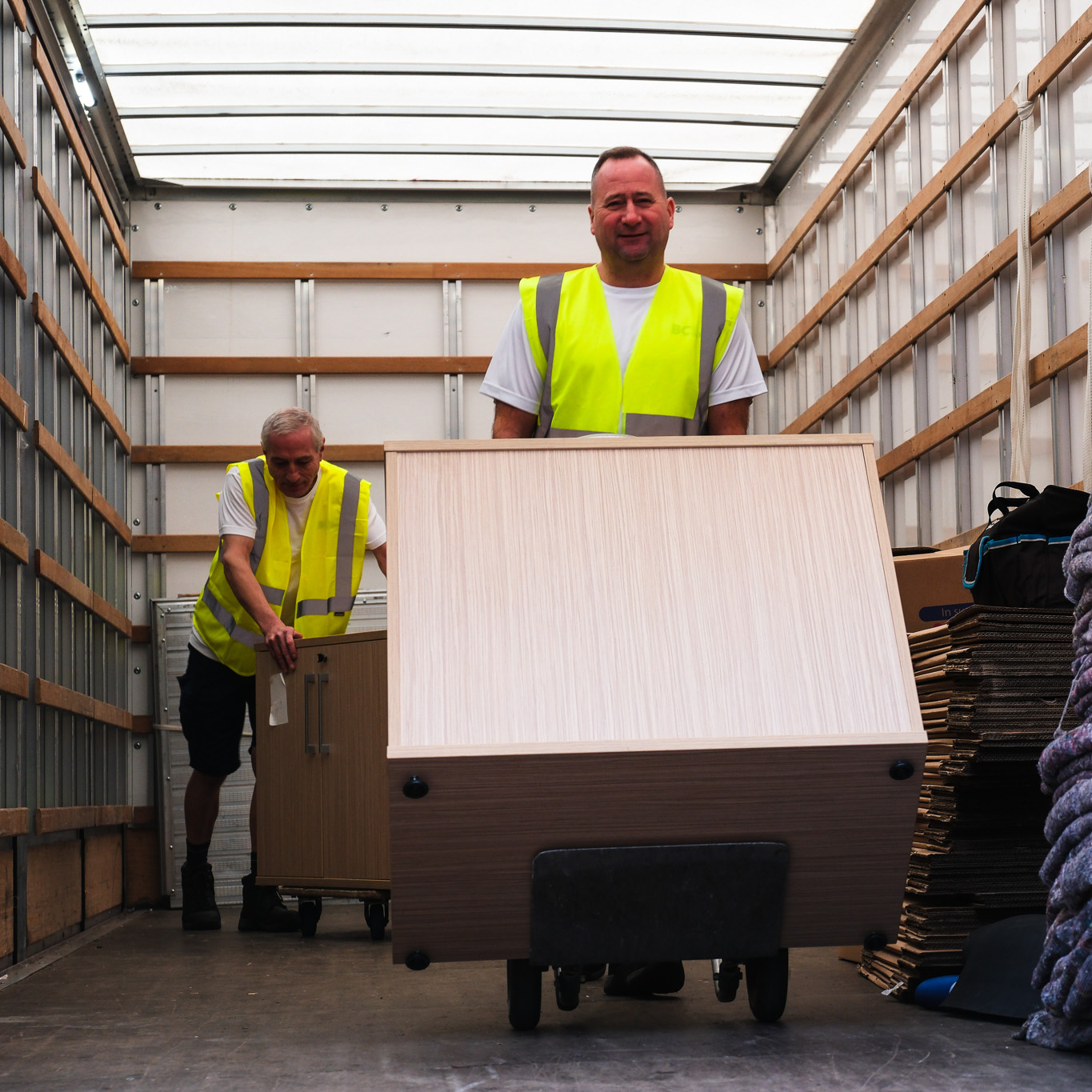 Removal team loading office furniture into a vehicle